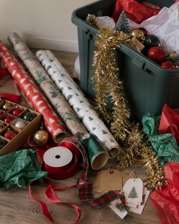 Rolls of wrapping paper, ornaments, ribbon, and a bin of decorations