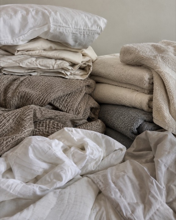 A stack of pillows, sheets, and folded towels